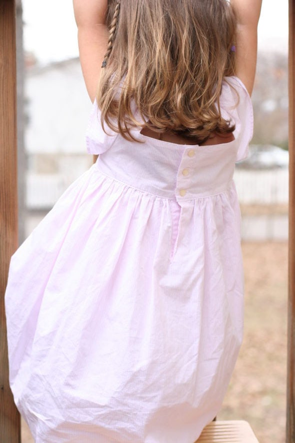 Little brown haired girl in a pink dress.