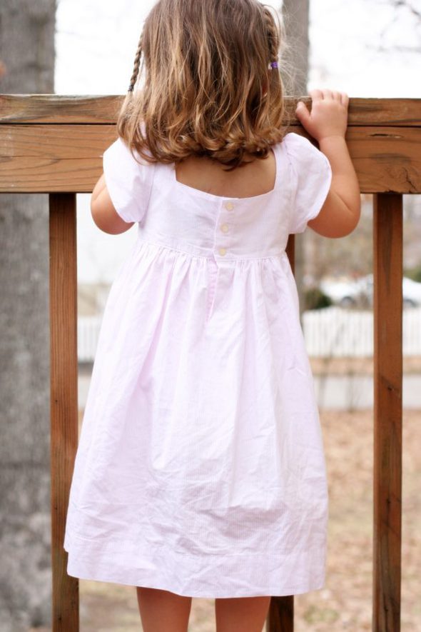 Zoe wearing a striped pink dress, facing away.