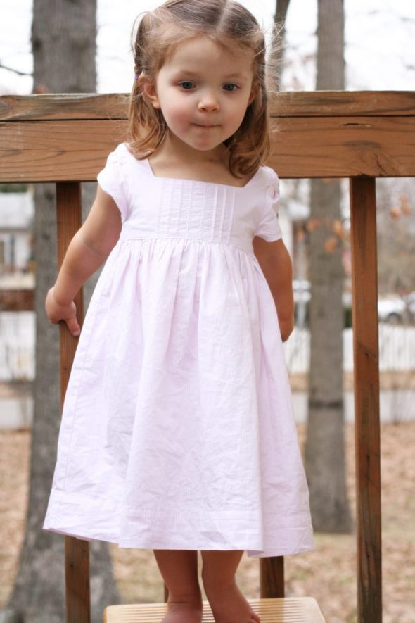 Zoe in a pink dress, facing the camera.