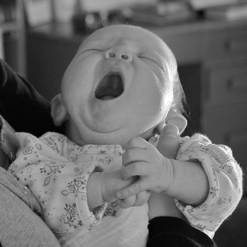 A black and white photo of a baby yawning.