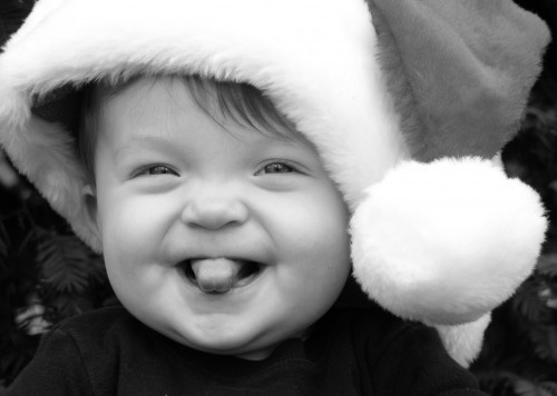 A baby girl in a Santa hat; photo is black and white.