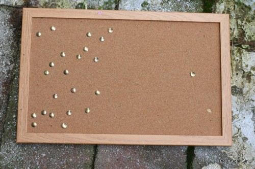 A brown bulletin board with thumbtacks in it.