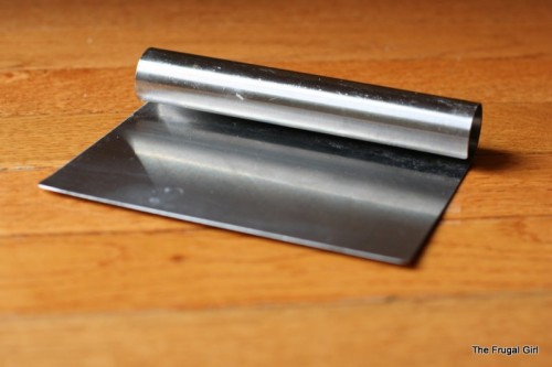 A metal bench knife on a wooden surface.
