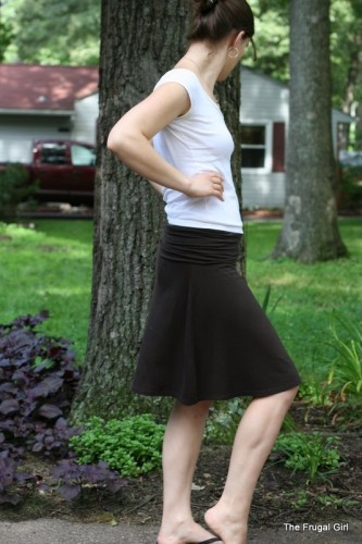 A woman in a white shirt and brown skirt, looking away from the camera