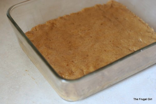 A person spreading filling in a glass dish.