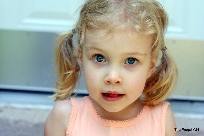 A little girl with blonde pigtails, looking at the camera.