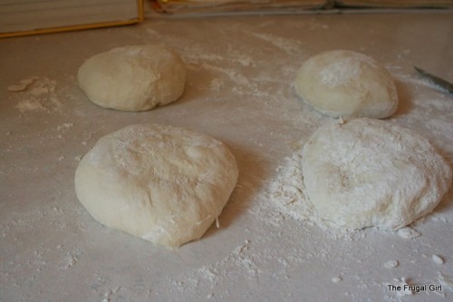 Three balls of pizza dough on a counter.