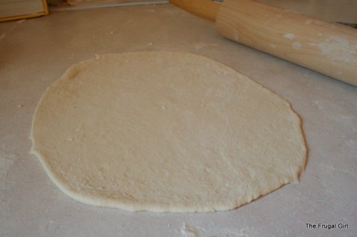 Pizza dough rolled out onto a counter.