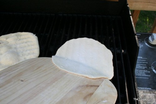 Dough sliding onto a grill from a pizza peel.