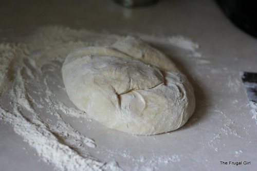 A ball of kneaded dough on a floury counter.
