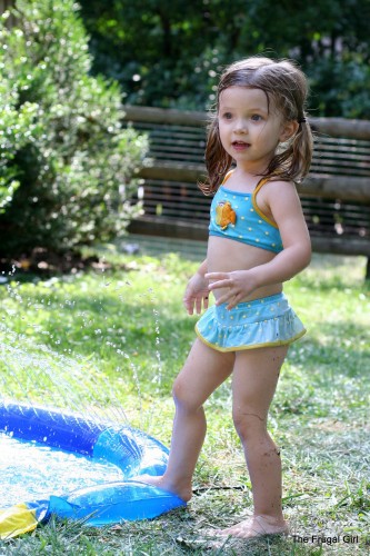 A little girl in a blue swimsuit with flippers on her feet.
