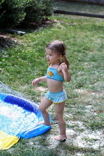 A ltitle girl stepping into a wading pool.