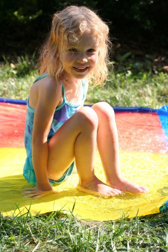 A little blonde girl on a slip and slide.