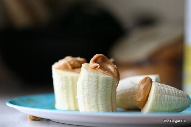 Banana chunks on a plate, topped with peanut butter.