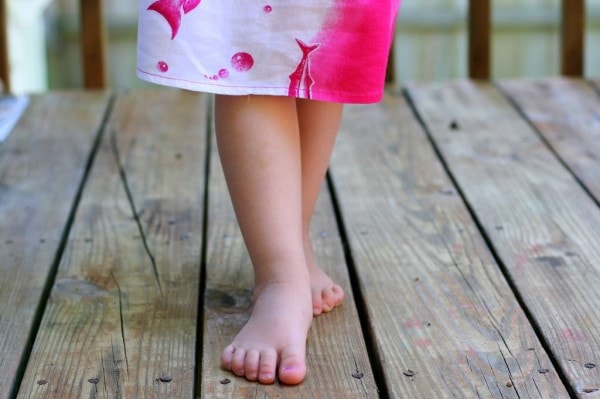 A barefoot girl in a white and pink dress.