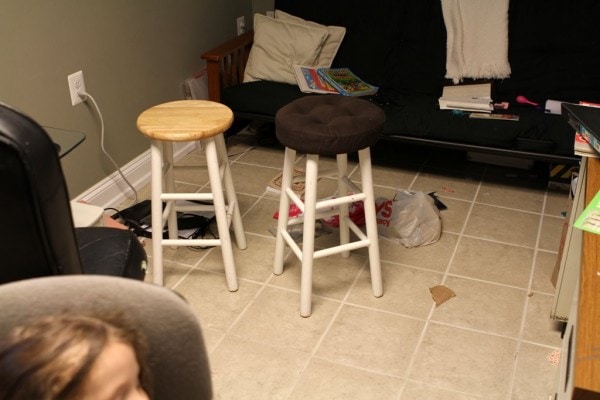 A tiled room with two bar stools in the middle.