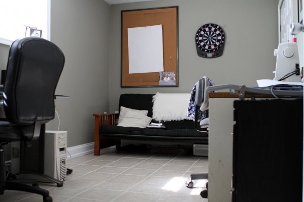 A green wall with a futon and a dartboard.