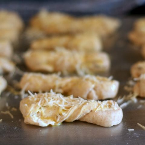 Italian cheese twists rising on a baking sheet.