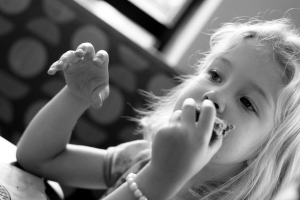 black and white photo of a girl eating a bagel.