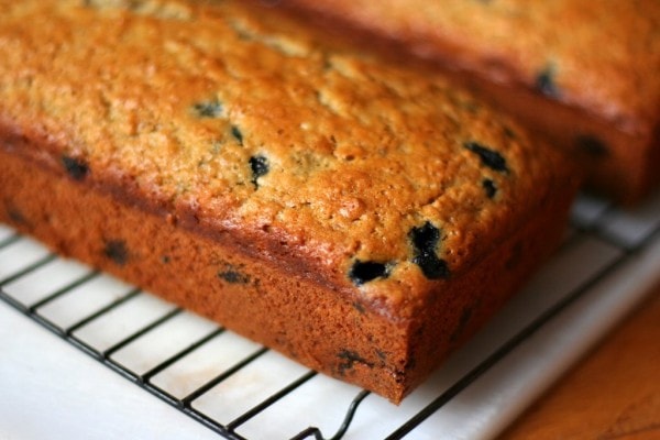 A loaf of blueberry bread on a cooling rack.