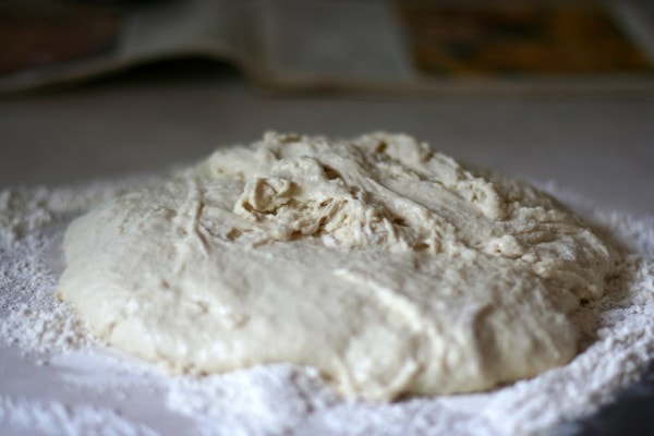 Un-kneaded bread dough on a floured counter.