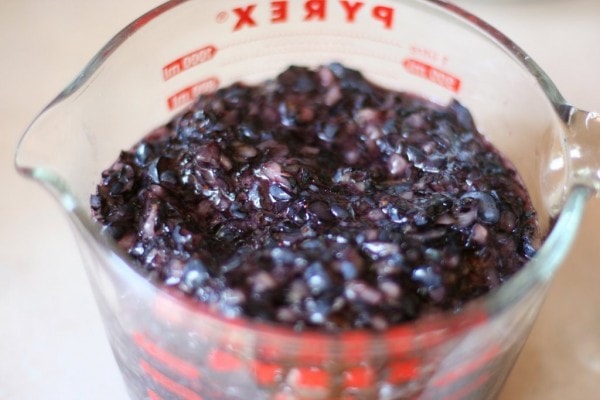 Mashed blueberries in a measuring cup.