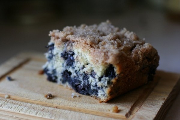A piece of blueberry coffeecake on a cutting board.