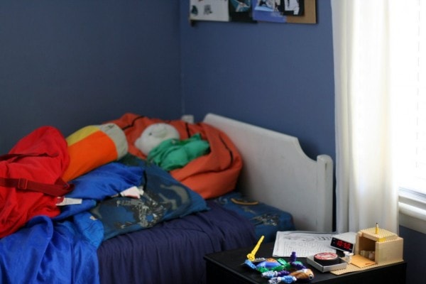 A white twin bed in a room with blue walls.