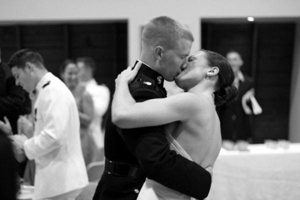 A couple kissing at a wedding, in black and white.