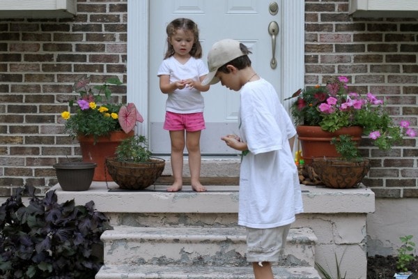 A boy and a girl setting off snappers on concrete steps.