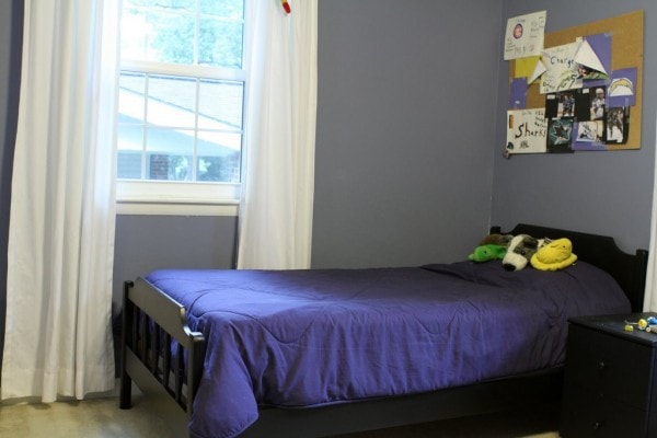 Black twin bed in a room with blue walls.