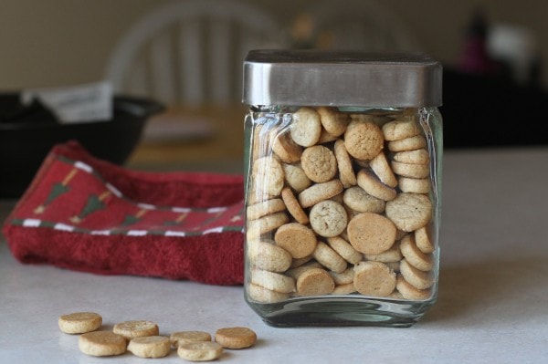 homemade pfeffernusse cookies in a square glass jar with a metal lid.
