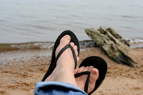 feet in flip flops by the beach.