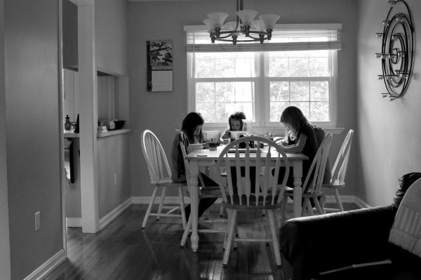 A black and white photo of kids at a dining room table.