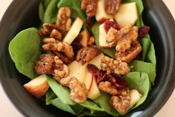 Nuts on top of a spinach salad.