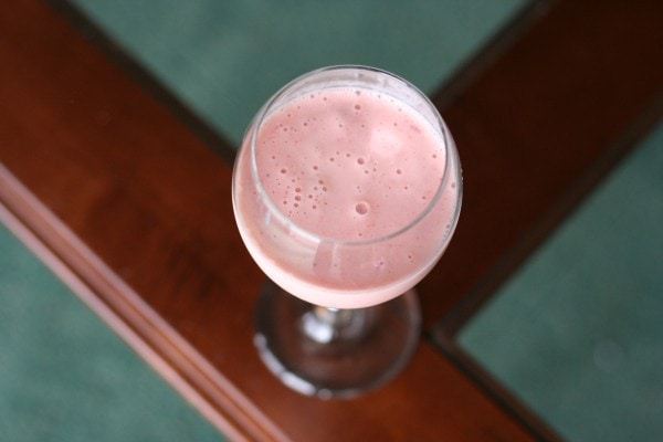 A pink smoothie in a wine glass.