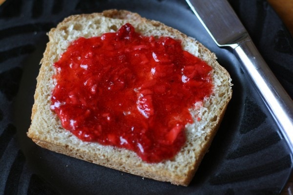 Strawberry jam spread on a slice of bread.