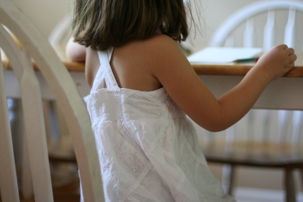 A little girl wearing a white sleevelss summer shirt.