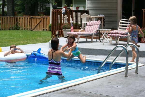 Kristen catching Zoe, who is jumping into the pool.