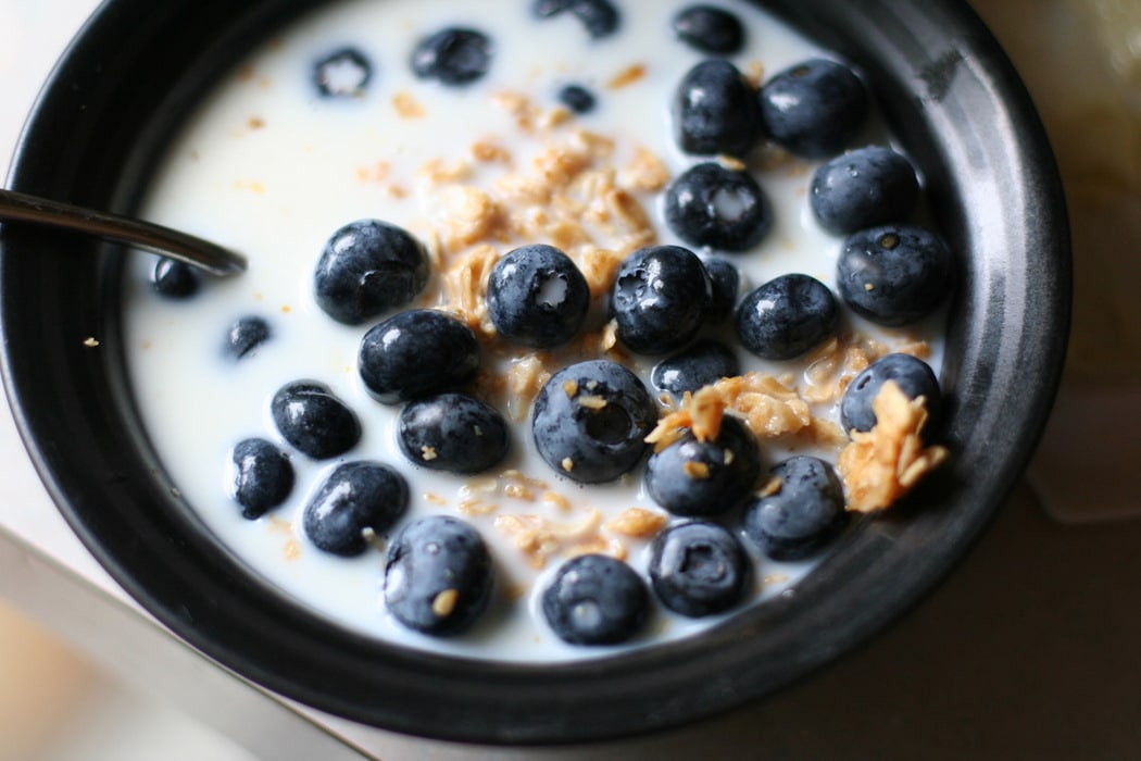 Blueberries and cereal in a black bowl.