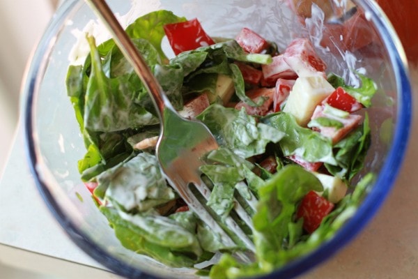 A spinach salad in a glass bowl.