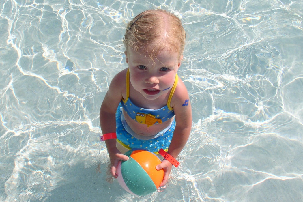 Little girl in a blue bikini in a pool.