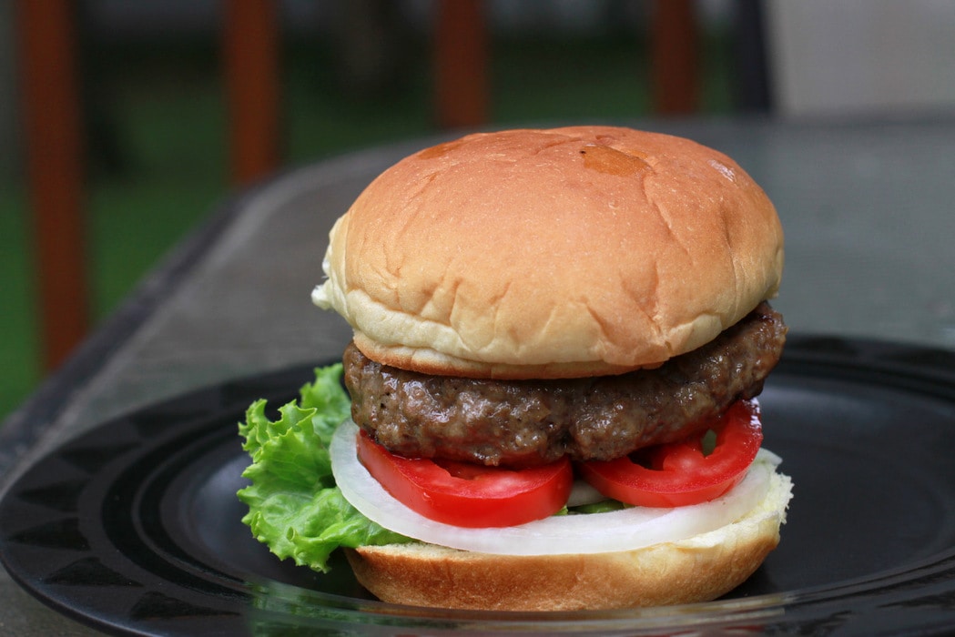 A burger in a bun with lettuce, tomato, and onion.
