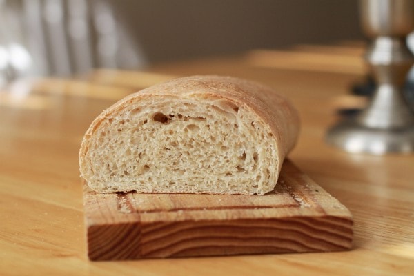 A sliced half loaf of French bread on a cutting board.