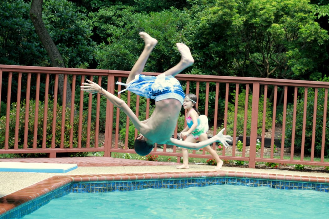 A kid doing a flip into a pool.