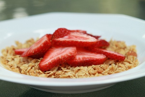 A bowl of granola topped with strawberries.