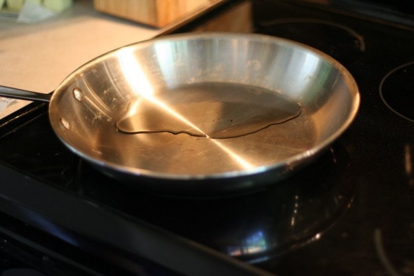 A skillet on a stove, with oil heating in it.