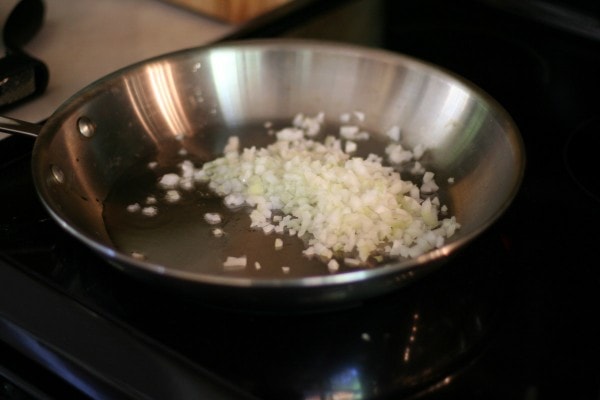 Onions being sauteed in a steel skillet.
