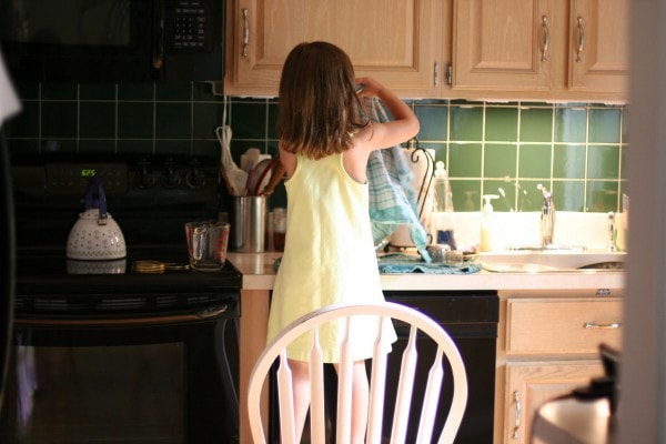 A little girl drying dishes.