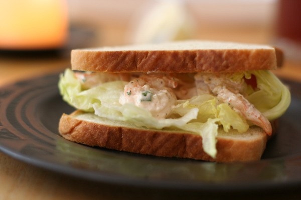A shrimp salad sandwich on a black plate.